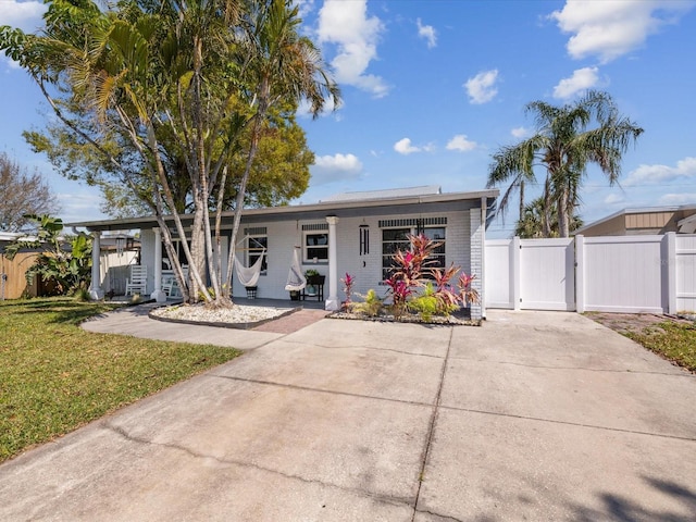 single story home featuring a gate, brick siding, fence, and a front lawn