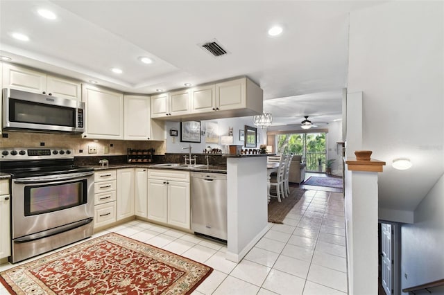 kitchen featuring light tile patterned floors, visible vents, appliances with stainless steel finishes, a sink, and a peninsula