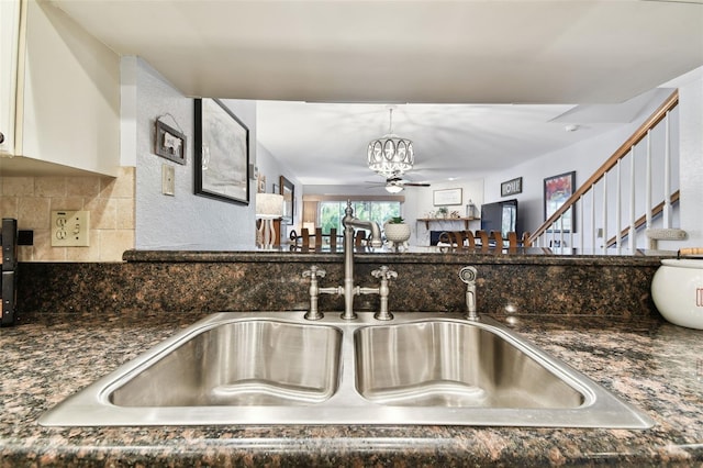 kitchen with dark stone countertops, pendant lighting, a sink, and decorative backsplash