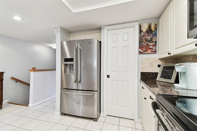 kitchen with tasteful backsplash, white cabinets, appliances with stainless steel finishes, dark stone countertops, and light tile patterned flooring