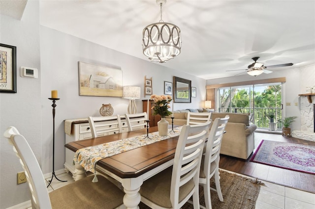 dining space featuring ceiling fan with notable chandelier and baseboards