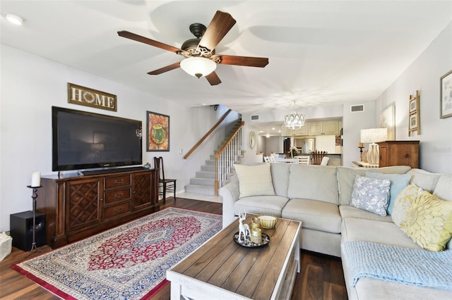 living room featuring stairs, visible vents, dark wood-style flooring, and ceiling fan with notable chandelier