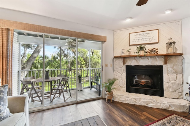 living room featuring ceiling fan, a fireplace, and dark wood-type flooring