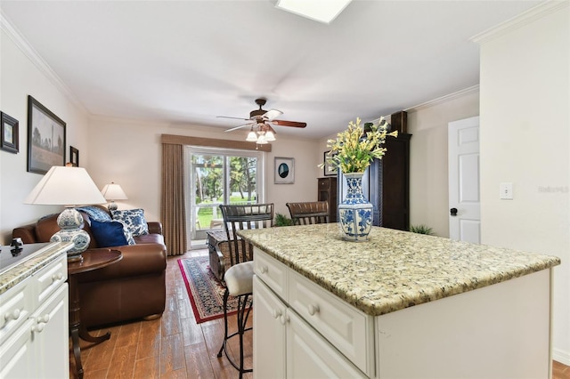 kitchen featuring dark wood-style flooring, open floor plan, white cabinetry, a kitchen island, and a kitchen bar