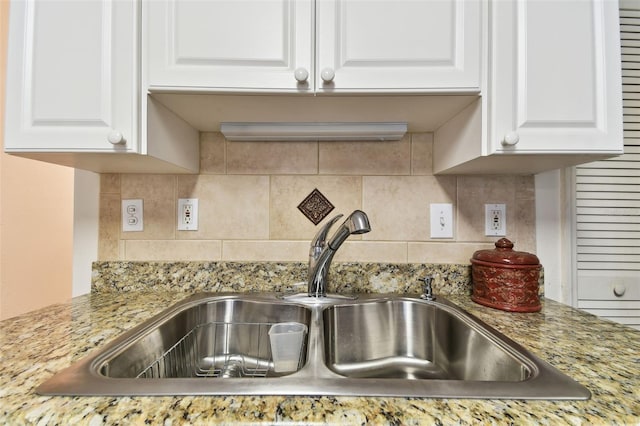 kitchen featuring backsplash, a sink, light stone countertops, and white cabinets