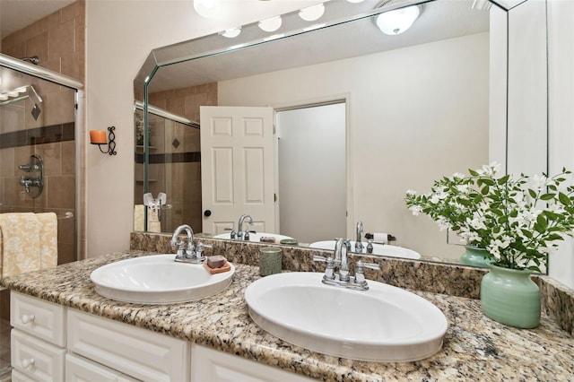 bathroom with double vanity, a sink, and a shower stall