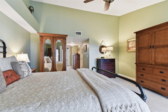 bedroom featuring light carpet, baseboards, visible vents, a ceiling fan, and a towering ceiling