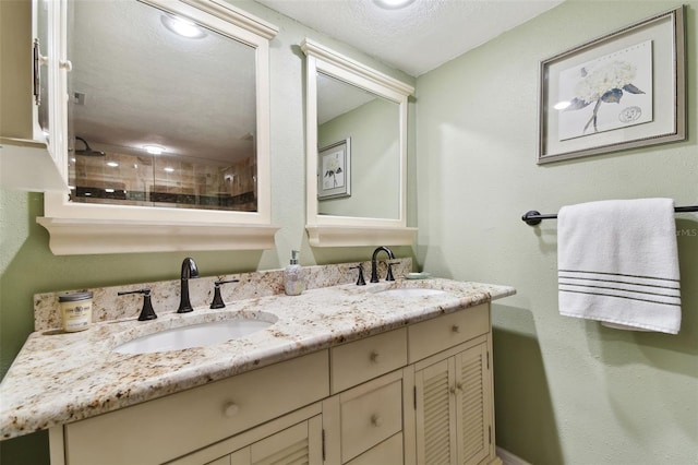 bathroom featuring a textured ceiling, double vanity, and a sink