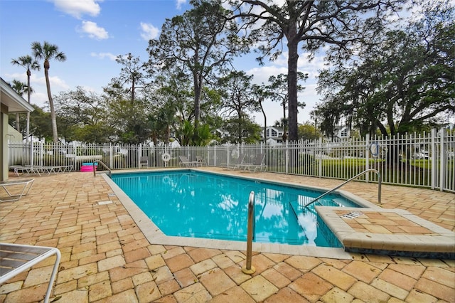 community pool with a patio area and fence