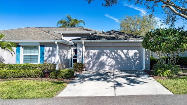 ranch-style home with stucco siding, a garage, roof with shingles, and driveway