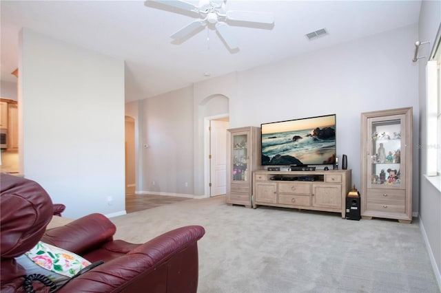 living area with light carpet, visible vents, arched walkways, and a ceiling fan