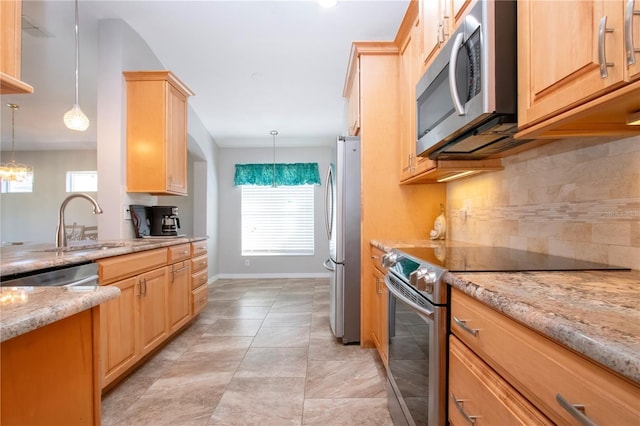 kitchen with decorative light fixtures, light stone countertops, light brown cabinetry, and stainless steel appliances