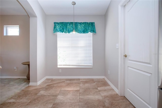 unfurnished dining area featuring arched walkways and baseboards