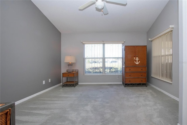 interior space featuring vaulted ceiling, carpet flooring, baseboards, and ceiling fan