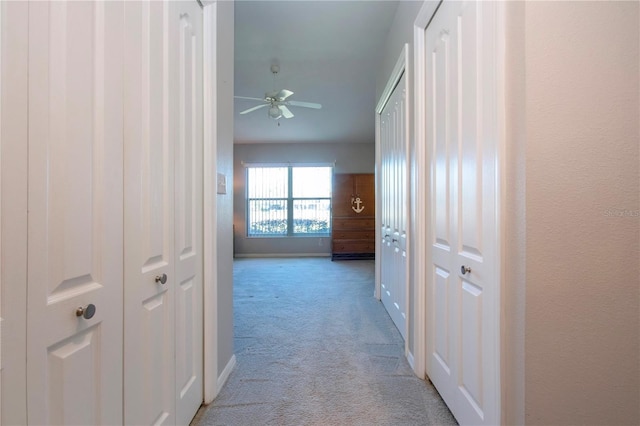 hall featuring baseboards and light colored carpet