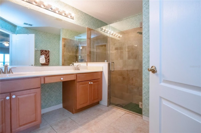 bathroom with visible vents, double vanity, a stall shower, a sink, and tile patterned floors