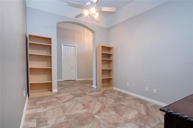 unfurnished bedroom with arched walkways, ceiling fan, and baseboards