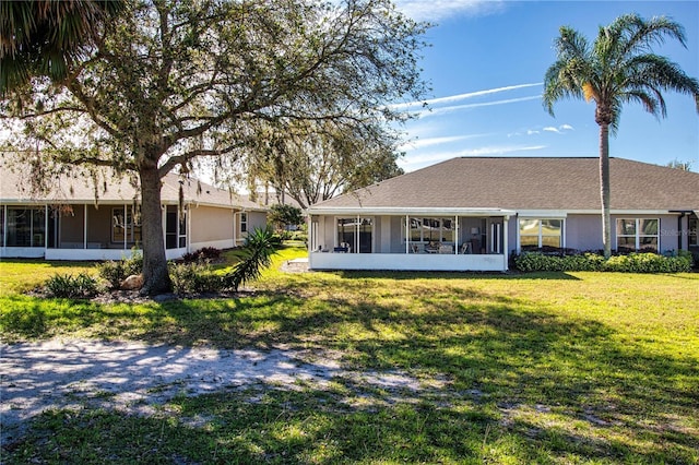 back of house with stucco siding, a yard, and a sunroom