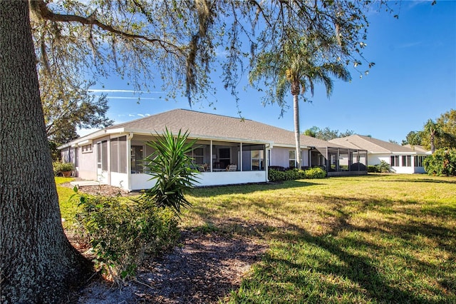 rear view of property with a lawn and a sunroom