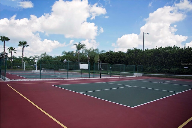 view of tennis court featuring community basketball court and fence