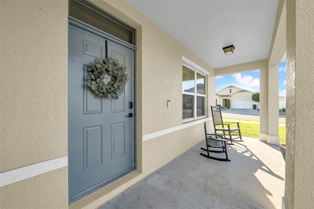 entrance to property with covered porch and stucco siding