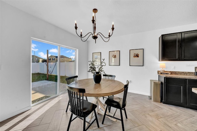 dining room featuring a notable chandelier and baseboards