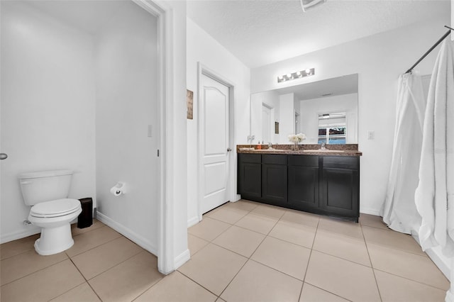 bathroom featuring toilet, vanity, a textured ceiling, tile patterned flooring, and baseboards