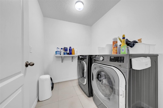 laundry area with laundry area, baseboards, washing machine and clothes dryer, a textured ceiling, and light tile patterned flooring