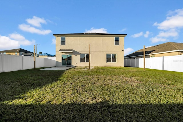 back of house with a yard, a patio area, a fenced backyard, and stucco siding