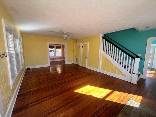 unfurnished living room with baseboards, visible vents, dark wood finished floors, stairway, and a textured ceiling