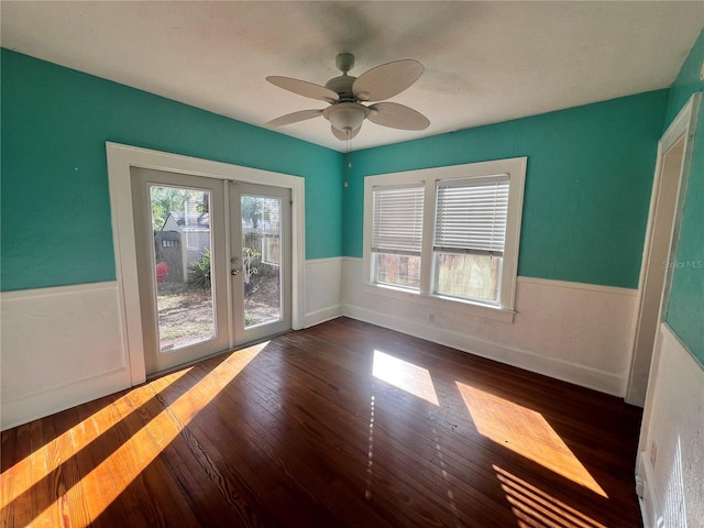 spare room with a wainscoted wall, french doors, plenty of natural light, and dark wood finished floors