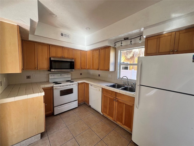 kitchen with white appliances, tasteful backsplash, visible vents, tile counters, and a sink