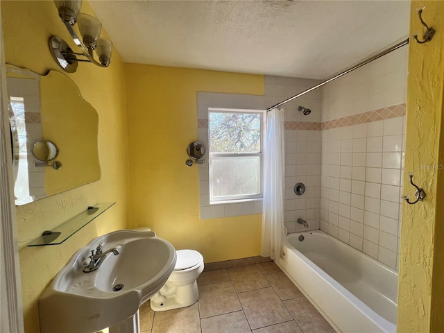 bathroom featuring a textured ceiling, tile patterned flooring, toilet, a sink, and shower / bath combo