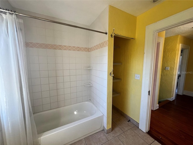 bathroom featuring shower / bath combination with curtain, baseboards, and tile patterned floors