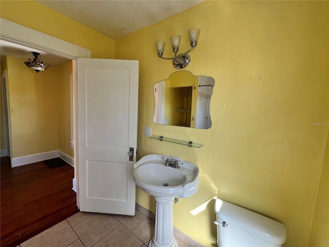 bathroom featuring tile patterned flooring, baseboards, a sink, and toilet