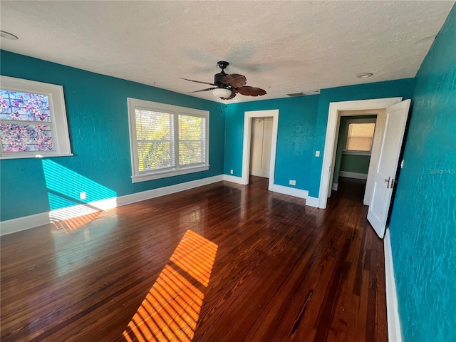 interior space with a textured ceiling, baseboards, and dark wood-type flooring