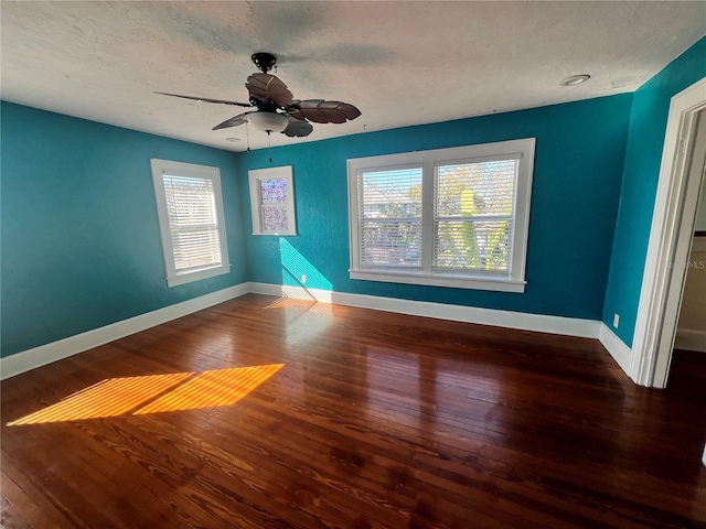 empty room featuring dark wood-style floors, a textured ceiling, baseboards, and a ceiling fan