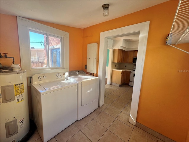 washroom with washing machine and dryer, electric water heater, light tile patterned flooring, laundry area, and baseboards