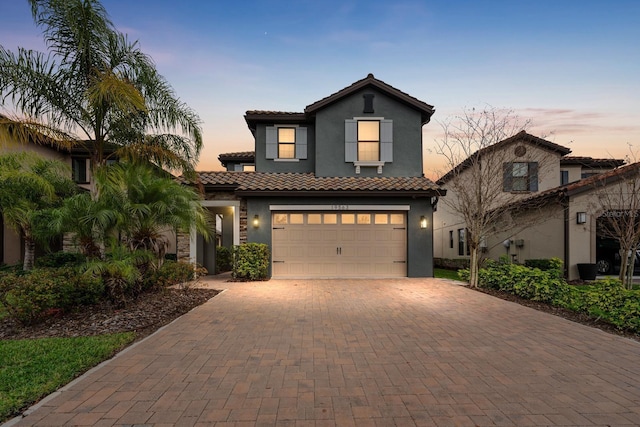 view of front of home featuring a garage, a tile roof, decorative driveway, and stucco siding