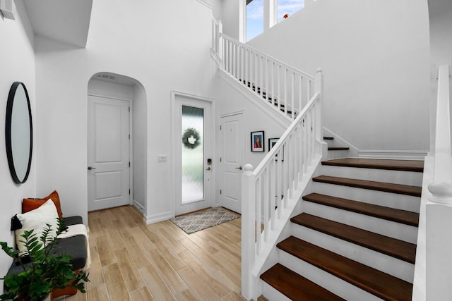 entrance foyer with a towering ceiling, baseboards, stairway, and wood finished floors