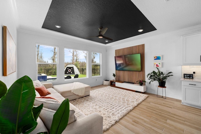 cinema with ceiling fan, a textured ceiling, baseboards, light wood finished floors, and crown molding