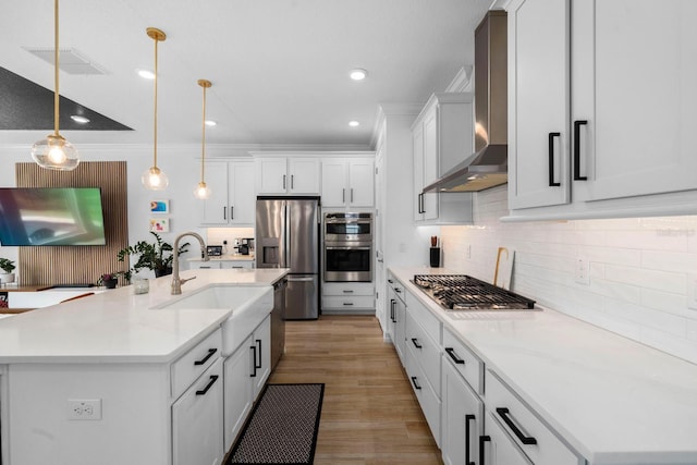 kitchen with visible vents, backsplash, appliances with stainless steel finishes, a sink, and wall chimney exhaust hood