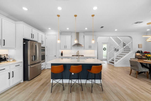 kitchen with stainless steel appliances, visible vents, a kitchen breakfast bar, light countertops, and wall chimney range hood