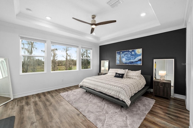 bedroom featuring baseboards, visible vents, a tray ceiling, and wood finished floors