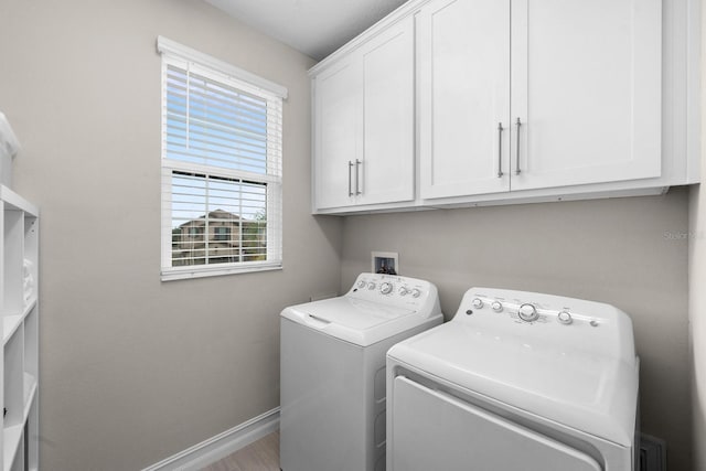 laundry area with cabinet space, baseboards, wood finished floors, and washing machine and clothes dryer