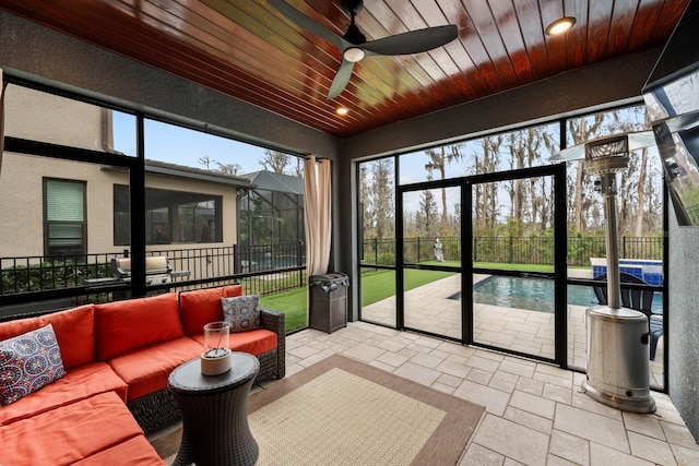 sunroom featuring wood ceiling and a ceiling fan