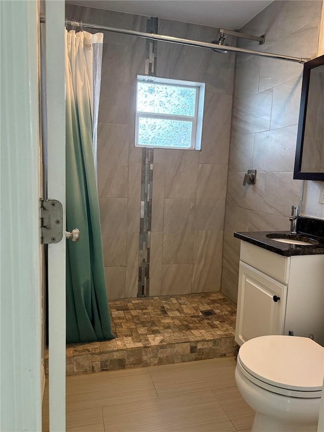 bathroom with tiled shower, vanity, and toilet