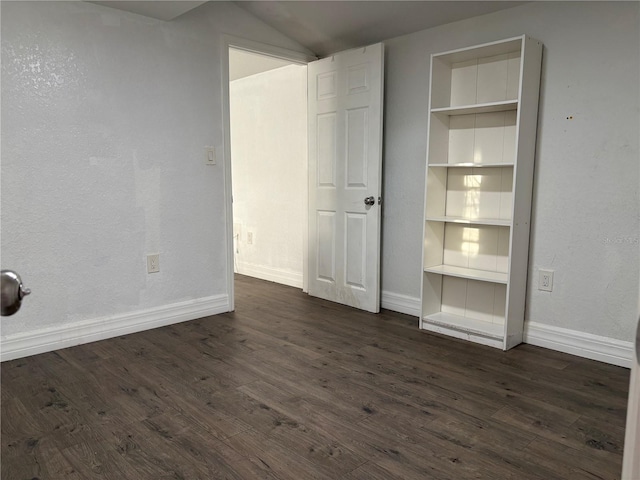 unfurnished bedroom with baseboards and dark wood-type flooring