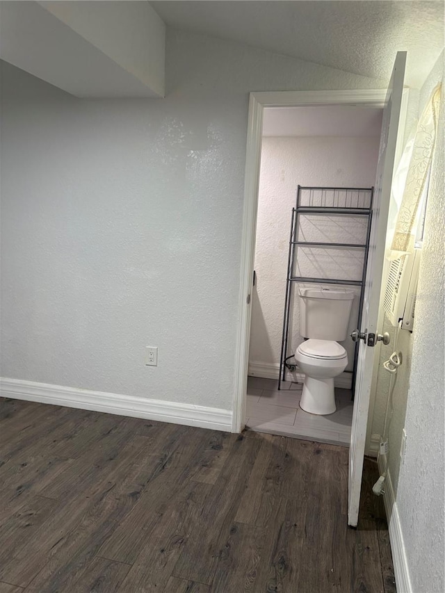 bathroom with wood finished floors, toilet, and baseboards