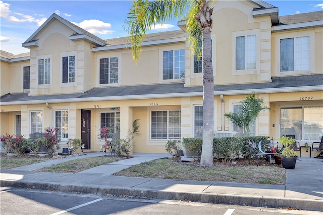 townhome / multi-family property with a shingled roof and stucco siding